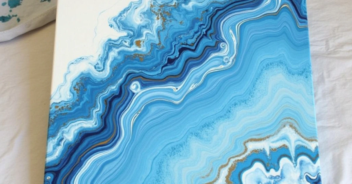 DIY wall art abstract pour painting on canvas in blue, white, and gold acrylics with marbled fluid design
